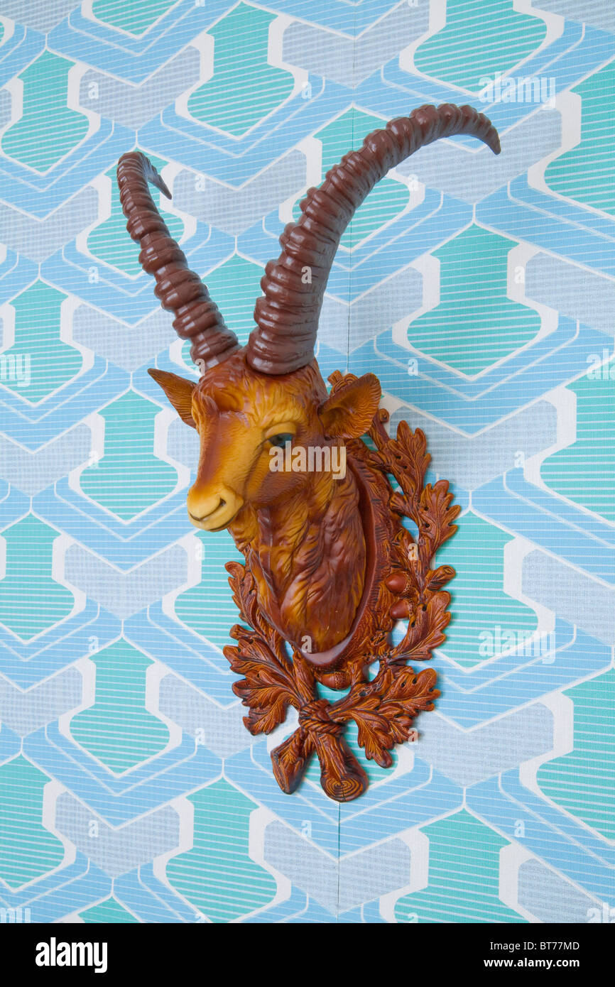 Plastic head of an ibex mounted on kitschy wallpaper from the 1960s or 1970s Stock Photo