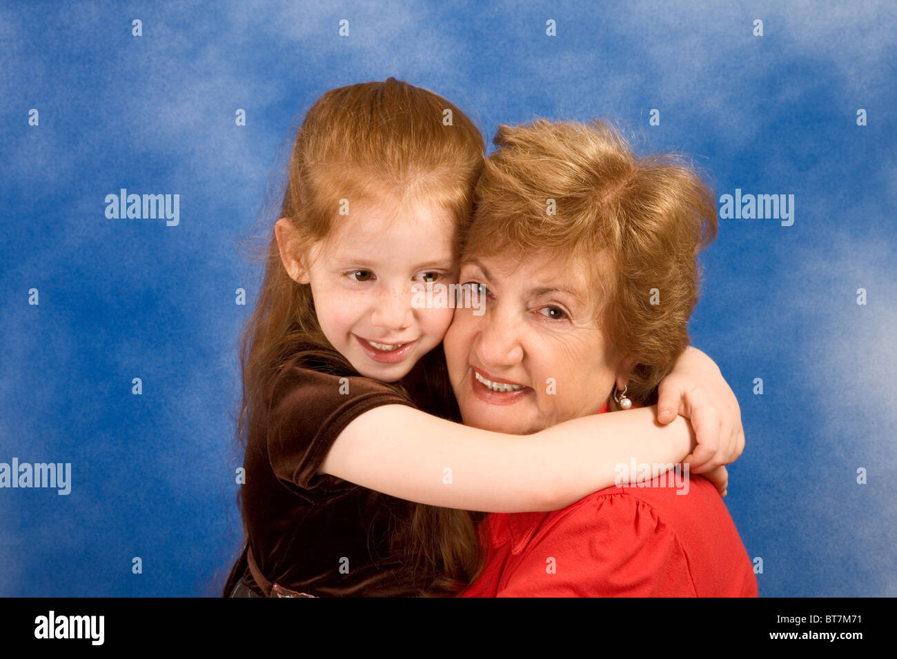 Portrait of grandmother hugging six year old girl smiling and happy Stock Photo