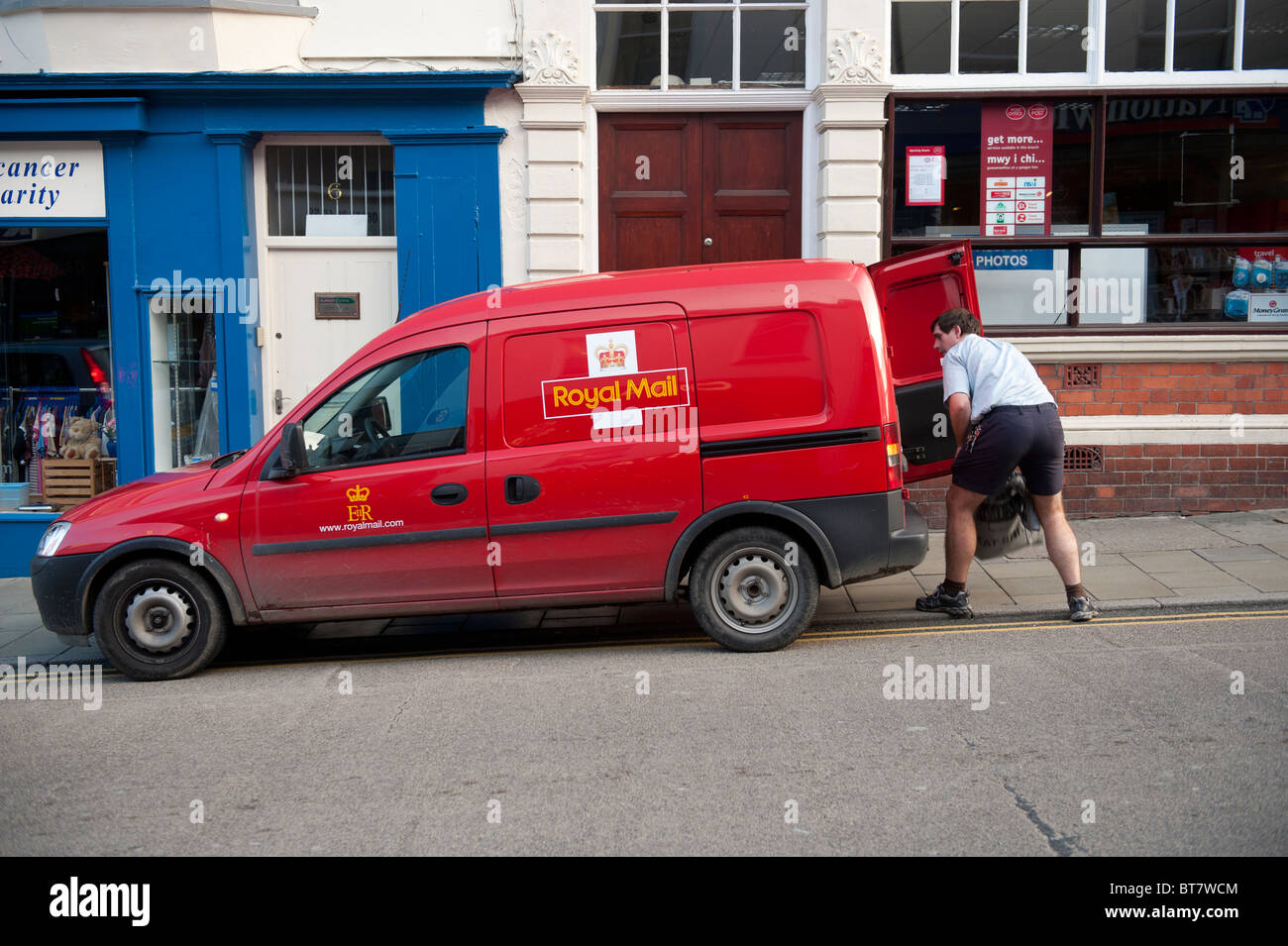 A postman loading a sack of mail into his van UK Stock Photo