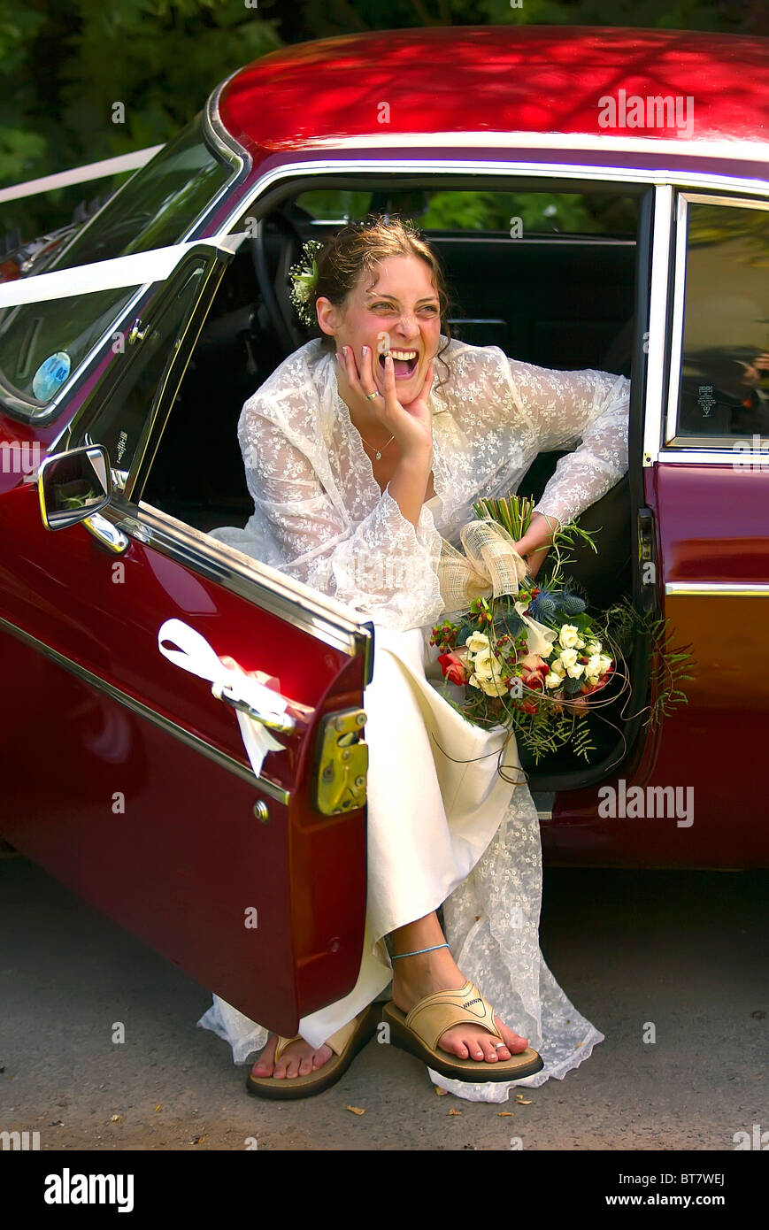 laughing young bride sat in MG sports car. Stock Photo