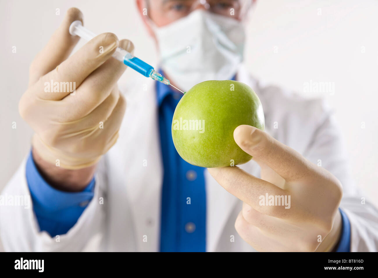 Man in a laboratory injecting liquid into an apple Stock Photo