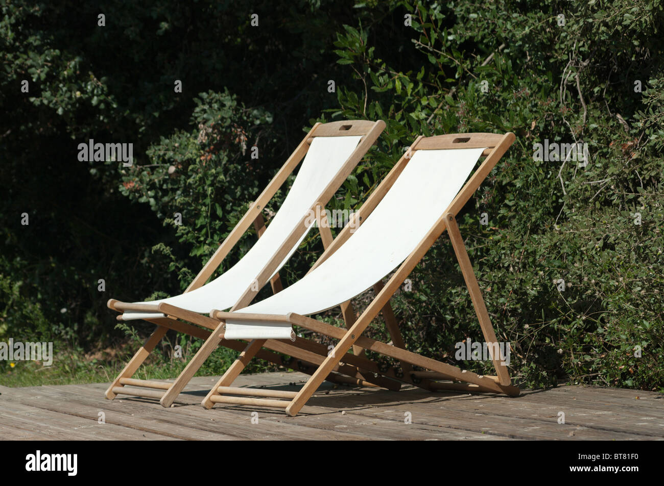 a pair of deck chairs sit empty in the sunlight Stock Photo Alamy