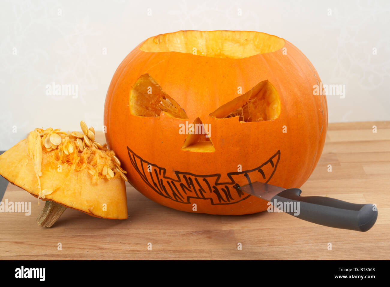 pumpkin ready to be turned into jack-o-lantern with cut outs drawn in pen with knives Stock Photo