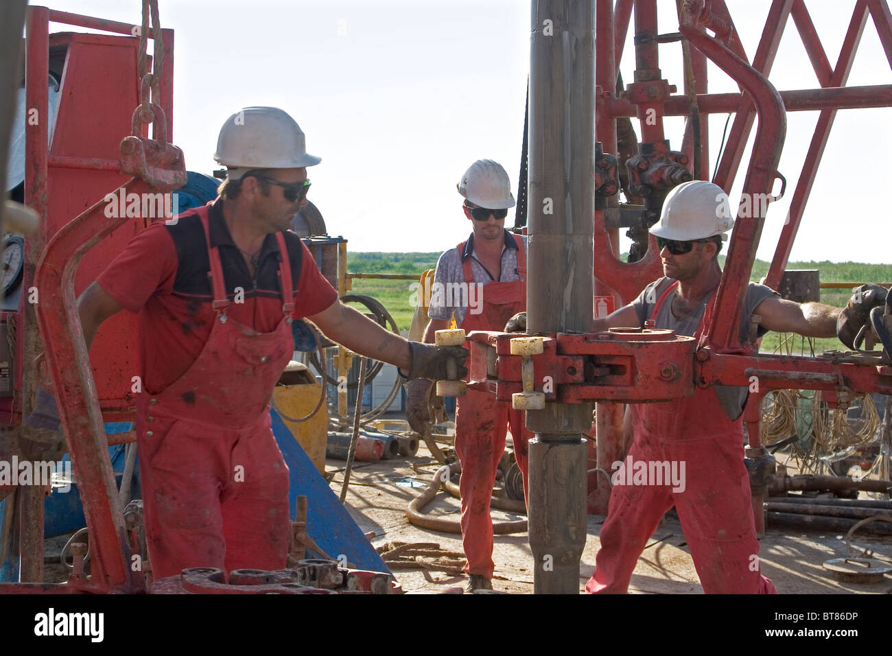 Onshore oil and gas exploration rig site with crewmen connecting casing