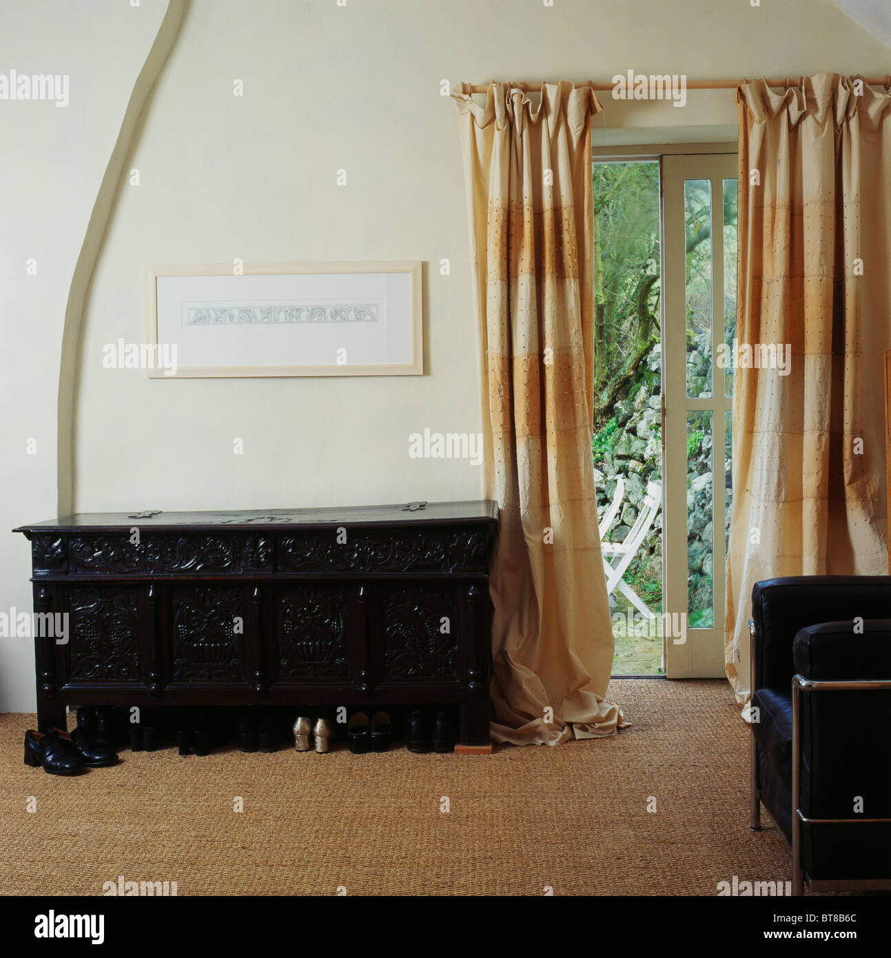 Carved Wooden Antique Chest Beside French Windows With Cream Stock