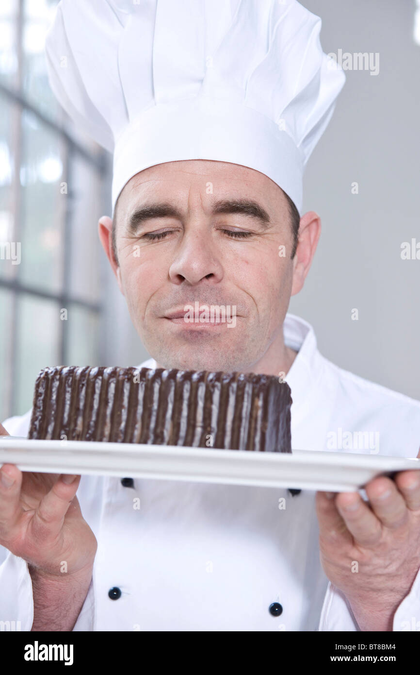 Confectioner smelling a chocolate cake appreciatively Stock Photo