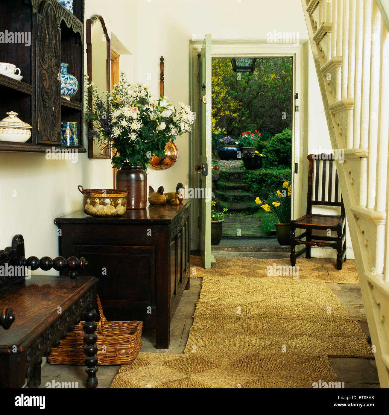 Rush matting and antique wooden chest in country hall with door open to