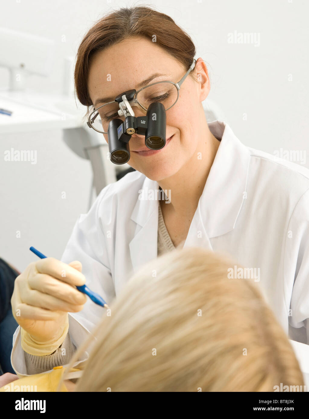 Dentist wearing magnifying glasses, treating a patient Stock Photo