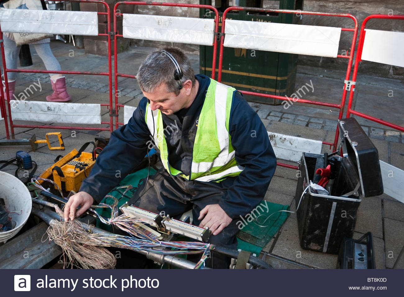 BT telephone engineer working in a manhole fixing phone lines in Stock