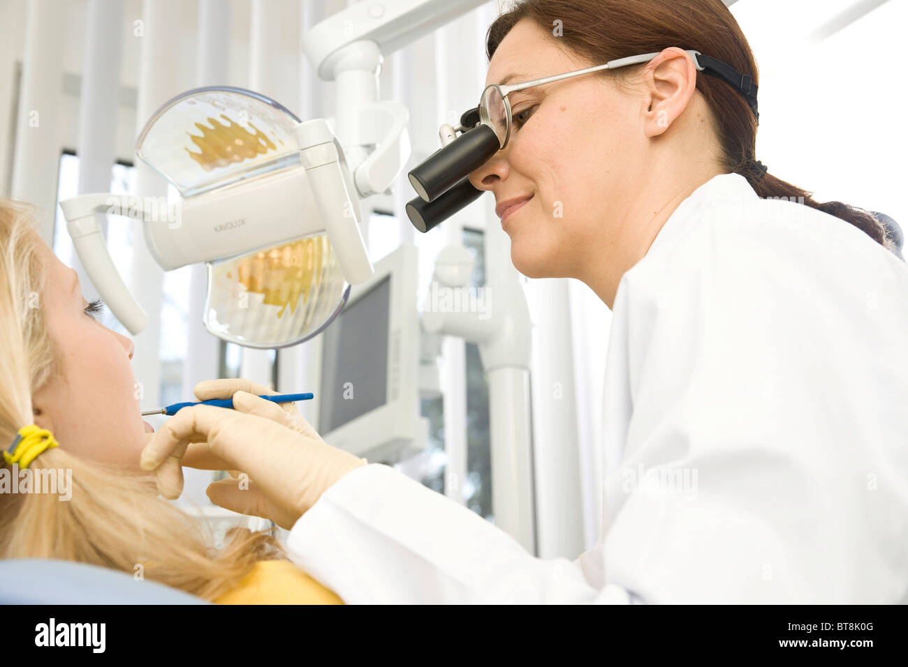 Dentist wearing magnifying glasses, treating a patient Stock Photo