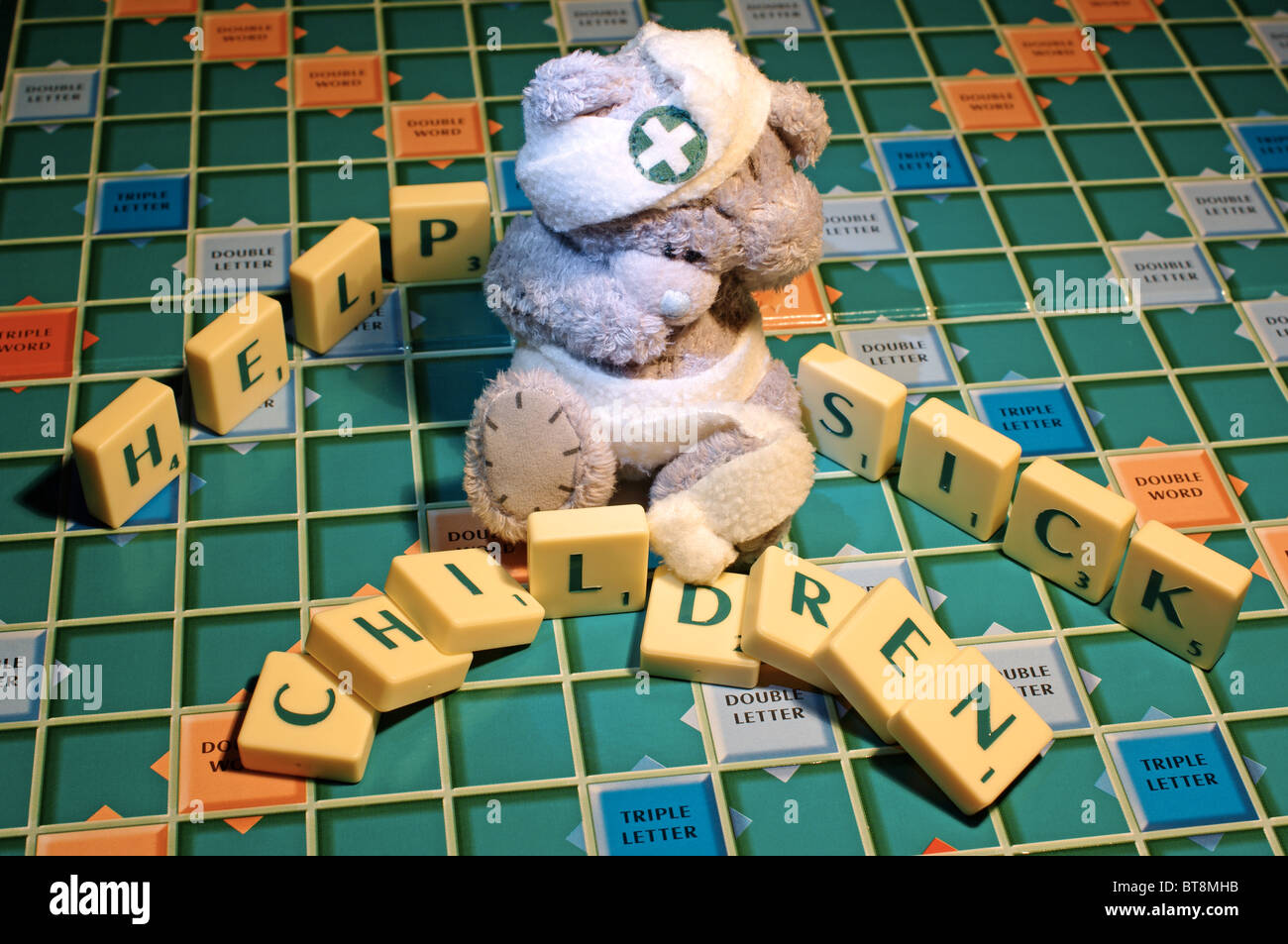 Childs teddy bear with scrabble letters, help sick children. Stock Photo