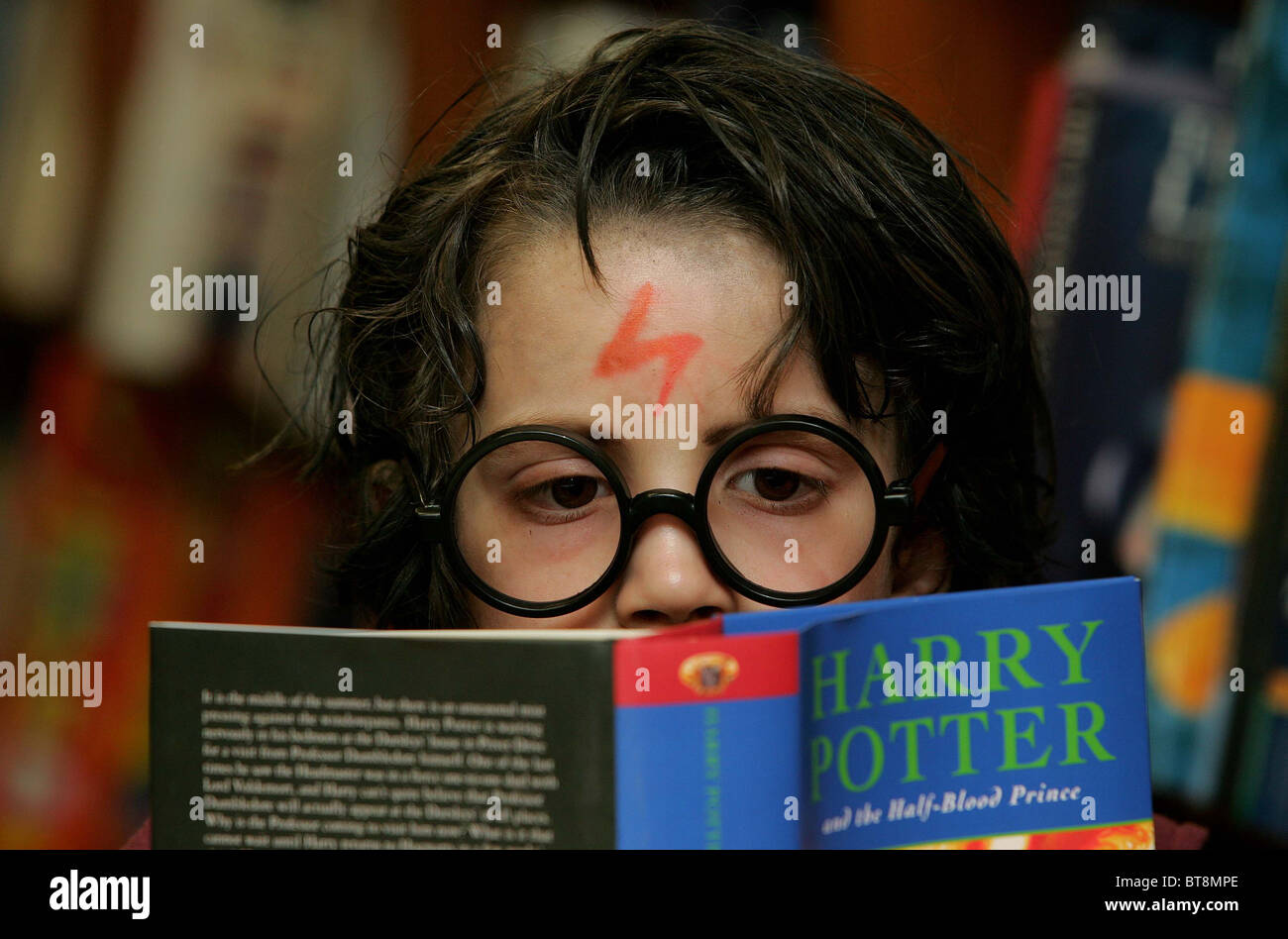 A young boy reading 'Harry Potter and the half blood prince' dressed up as Harry Potter Picture by James Boardman Stock Photo