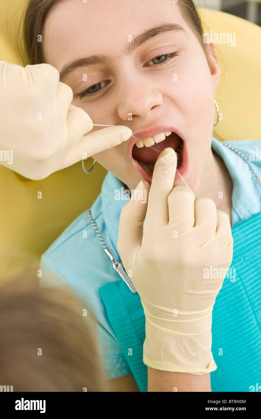 Dental nurse cleaning a girl's teeth with dental floss Stock Photo Alamy