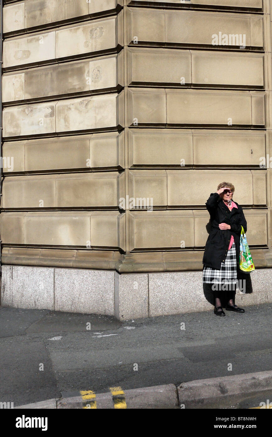 elderly lady waiting on a street corner in the UK Stock Photo