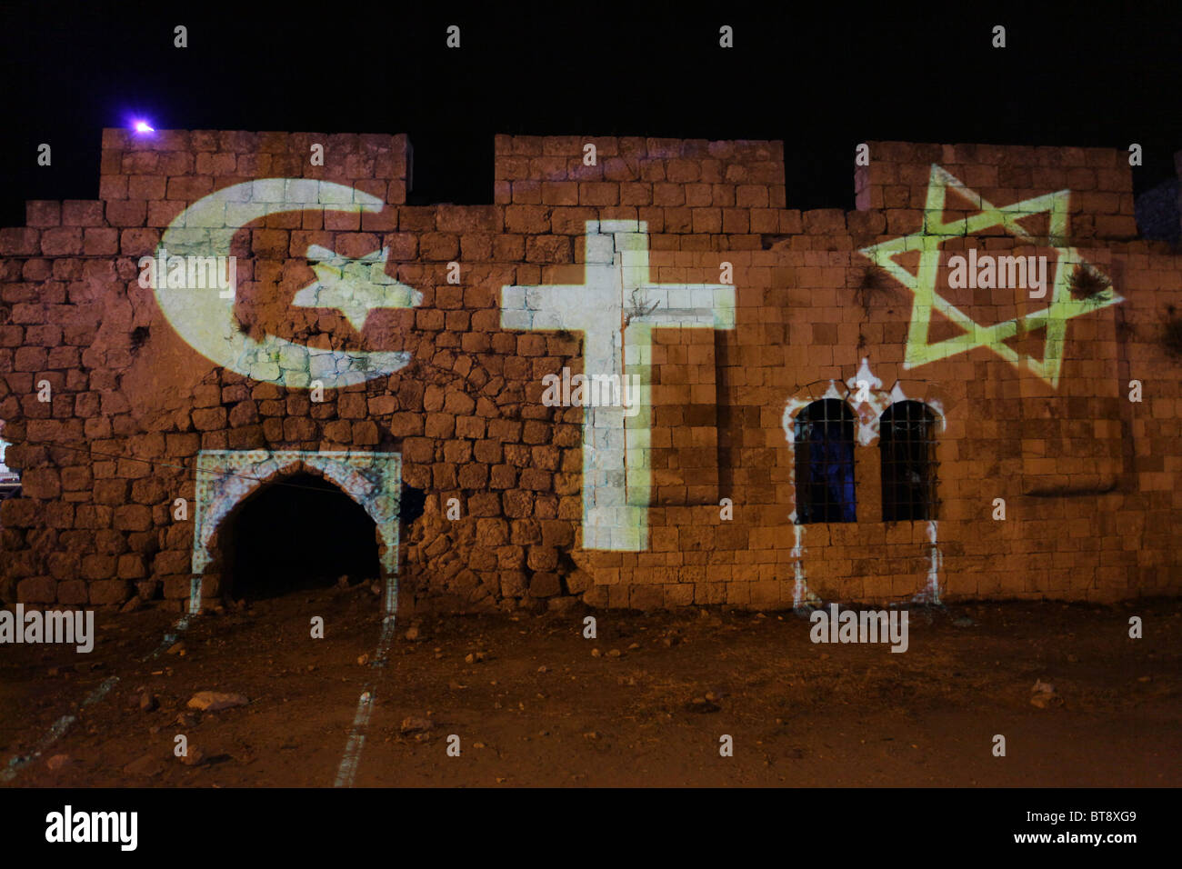 Symbols of the three Abrahamic religions: Islam, Judaism, and Christianity are projected on an deserted house which belonged to Palestinians who fled or were expelled during the 1948 Israel War of Independence in the historic center of the mixed Israeli-Arab city of Lod (Arabic al-Lidd) in Israel Stock Photo