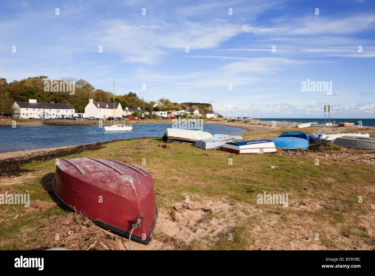 Upturned boats with view to The Ship Inn and village across small harbour in Red Wharf Bay, Isle of Anglesey, North Wales, UK. Stock Photo