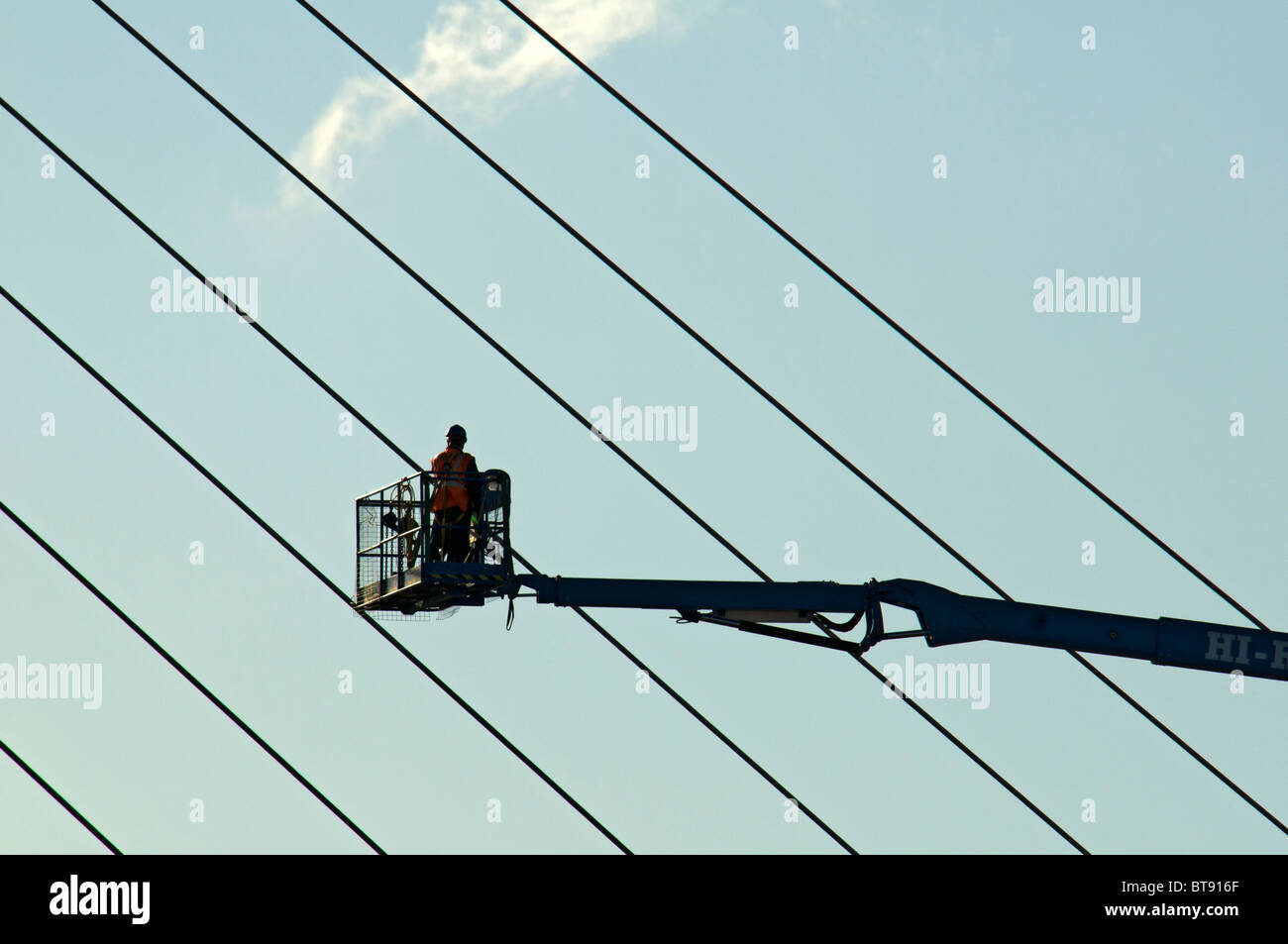 High reach access platform (cherry picker) working on a cable stayed footbridge at Salford Quays, Manchester, England, UK Stock Photo