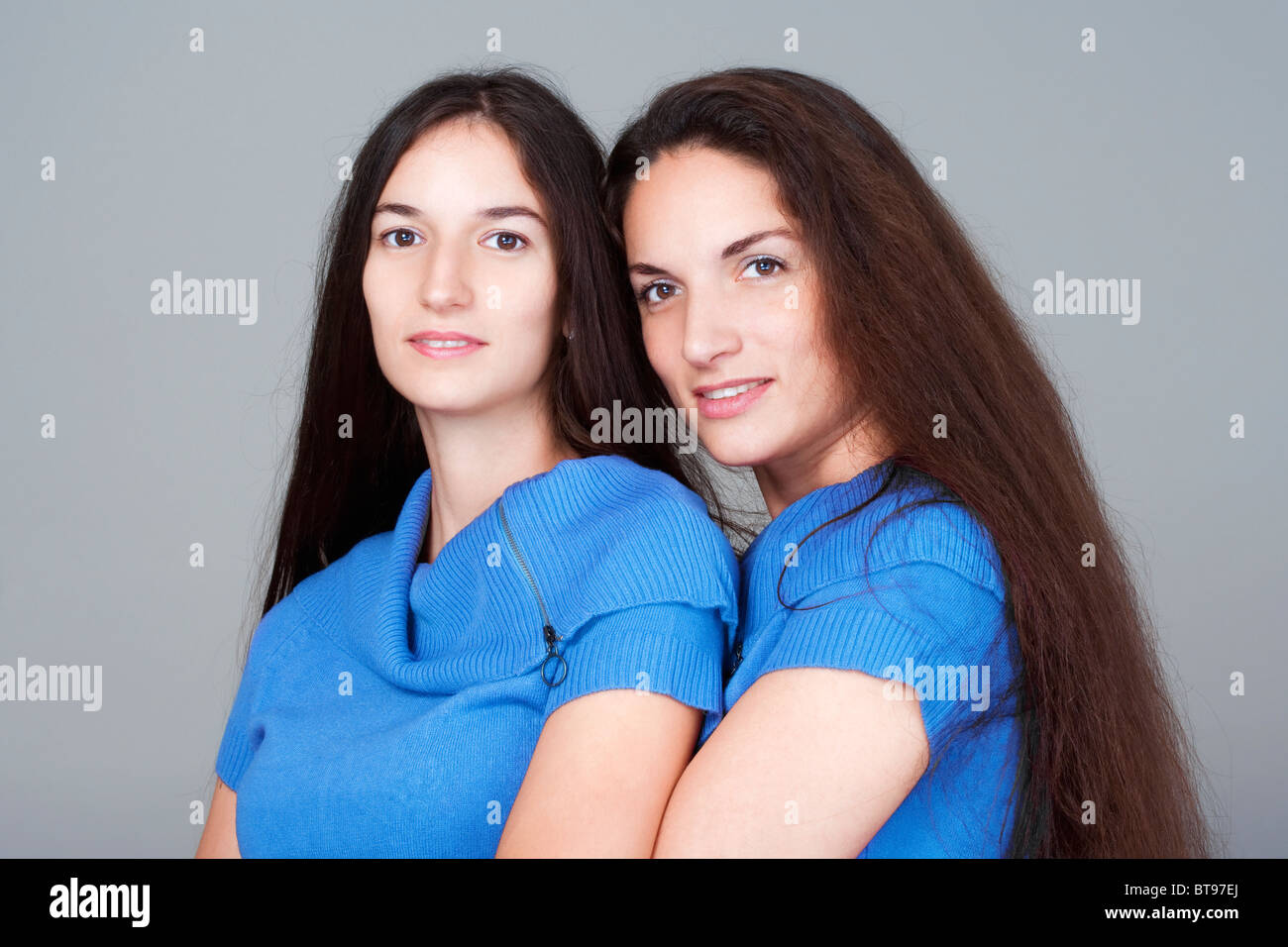 portrait-of-two-sisters-with-very-long-brown-hair-isolated-on-gray