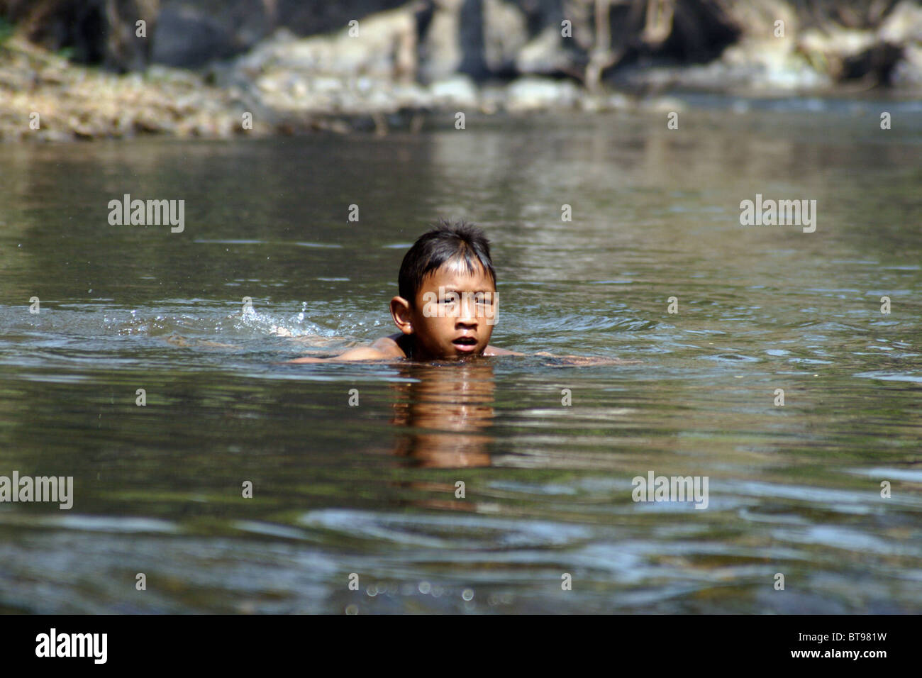 A young Asian boy is swimming in a beautiful river in Pang Ma Pha