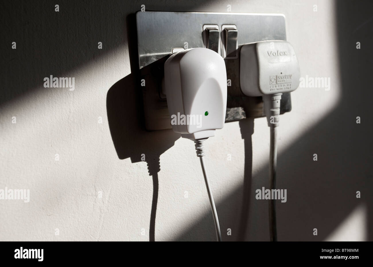 Plugs connected to electrical wall socket, London, England, UK Stock
