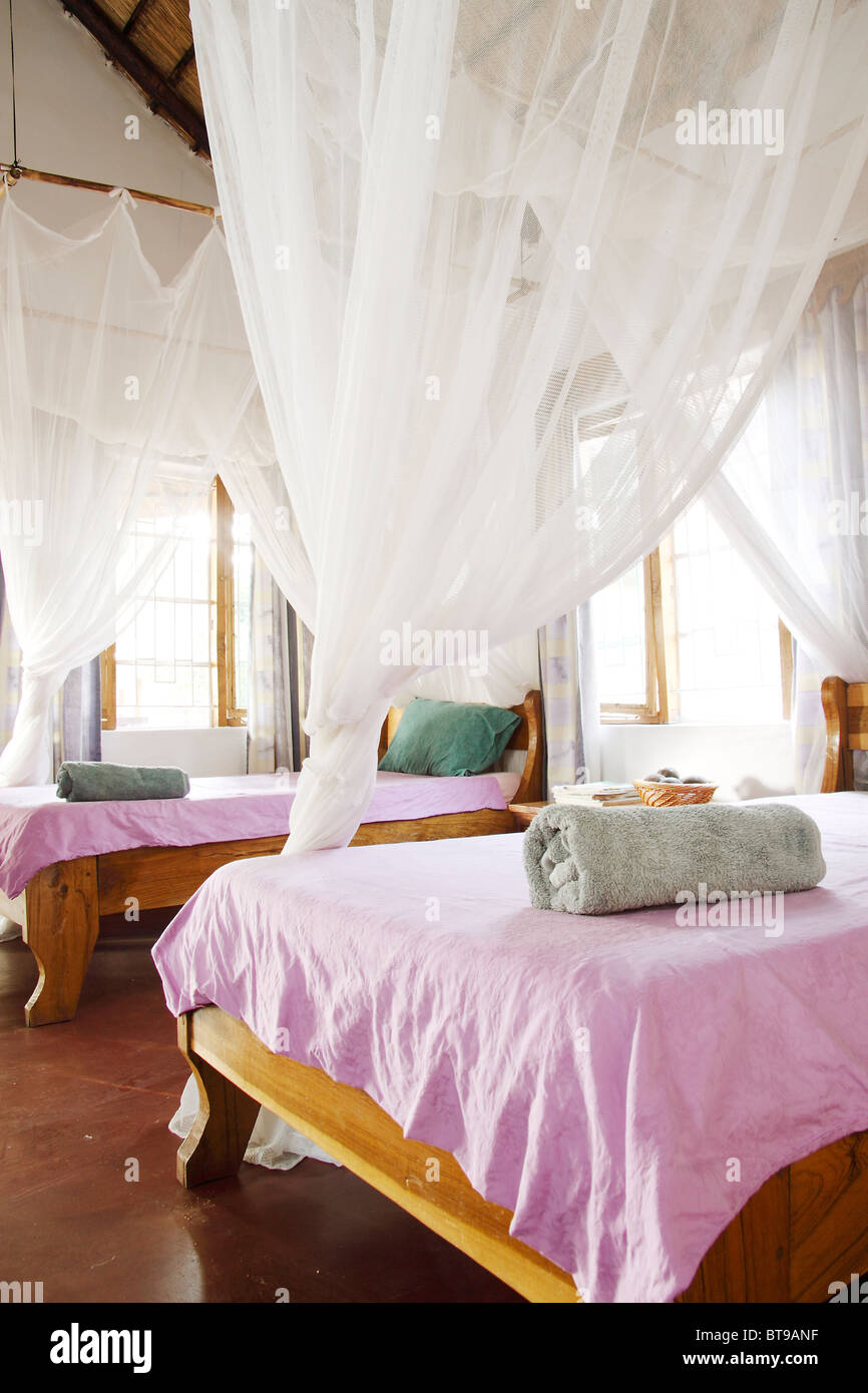 Two Twin Beds with Towels and Gauzy Drapes/Bug Nets. Vertical
