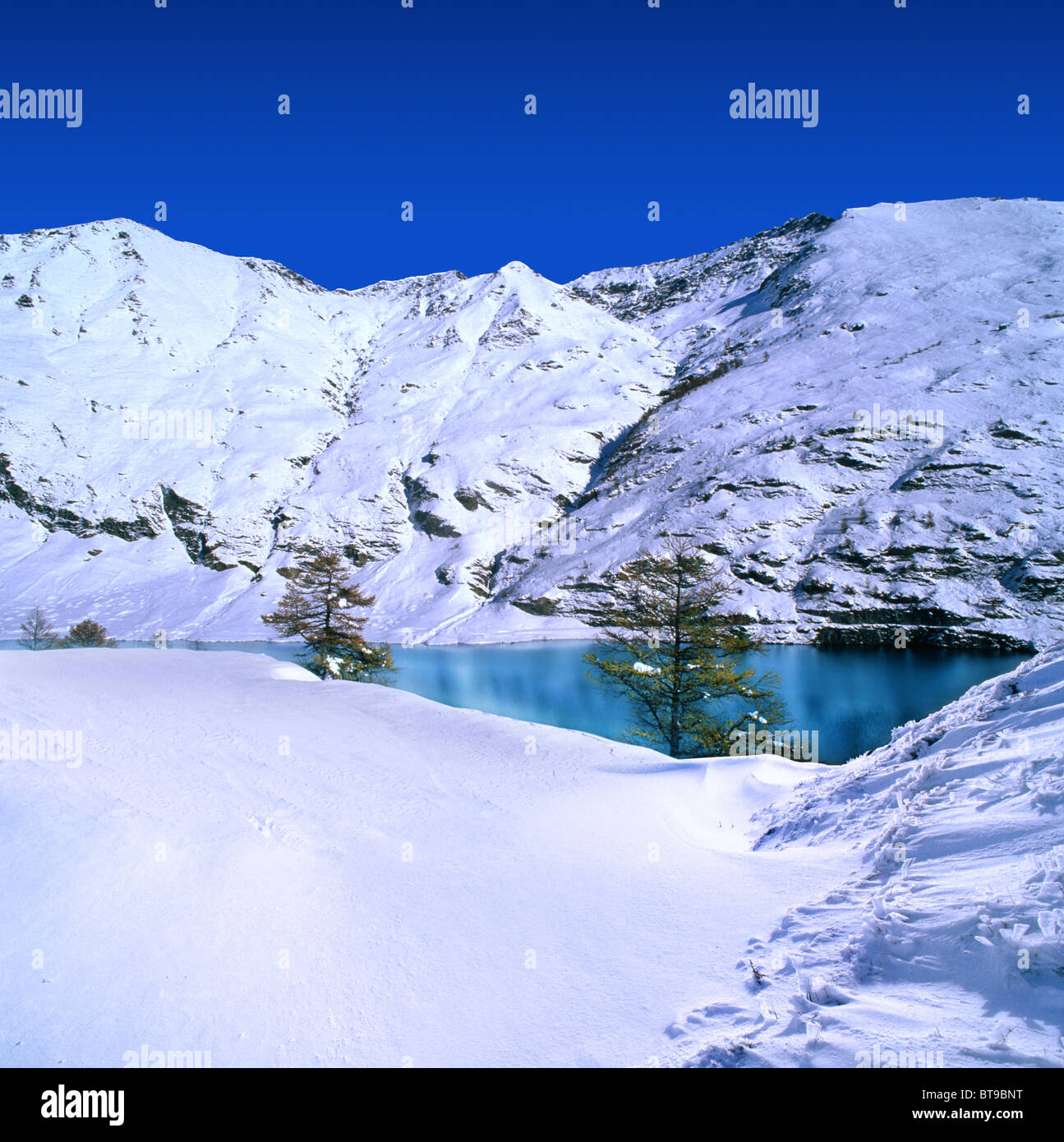 Snow covered mountains with a blue sky and azure lake Stock Photo