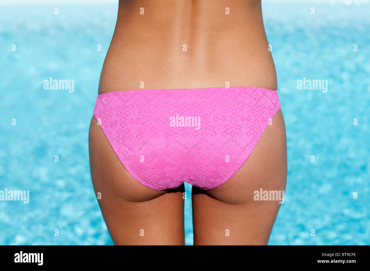 A young woman in a pink bikini by a pool, rear view Stock Photo