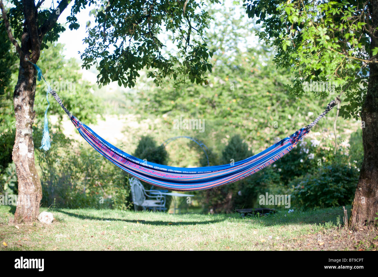 A hammock between two trees in a garden Stock Photo