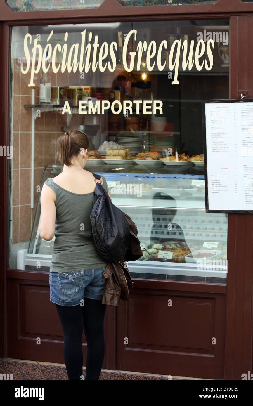 Woman looking through a window of a  Greek Food shop in Paris, France Stock Photo