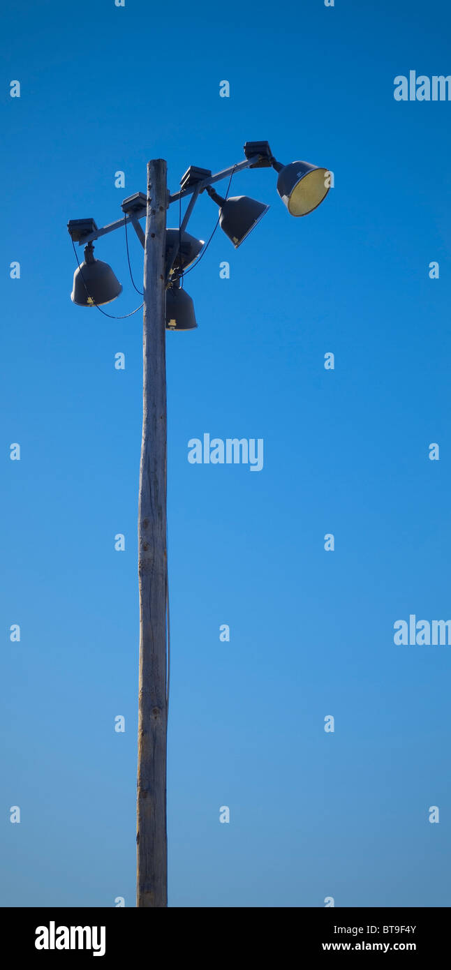 A older wooden pole of lights in a baseball field lighting system, on a clear blue sky day Stock
