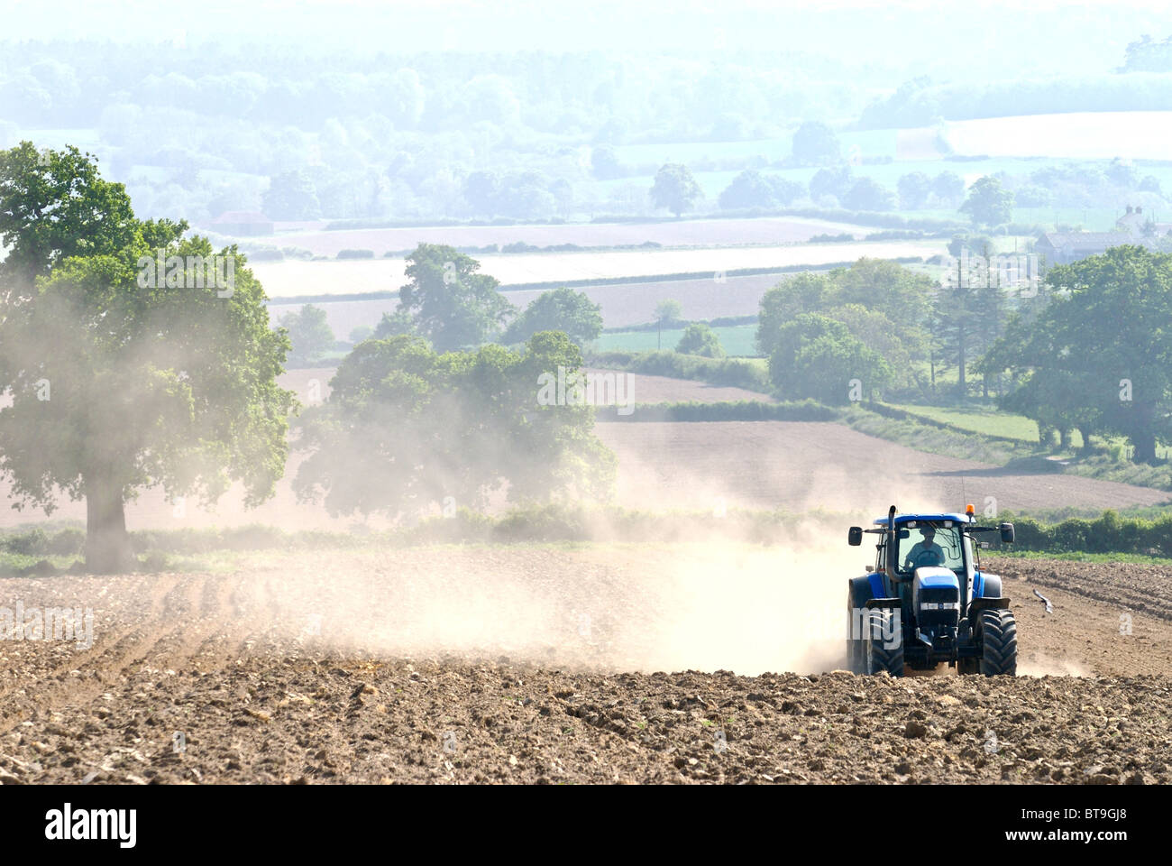 Tractor working on dry land in Sussex pulverising the soil and creating clouds of dust which is blown in the wind. Stock Photo