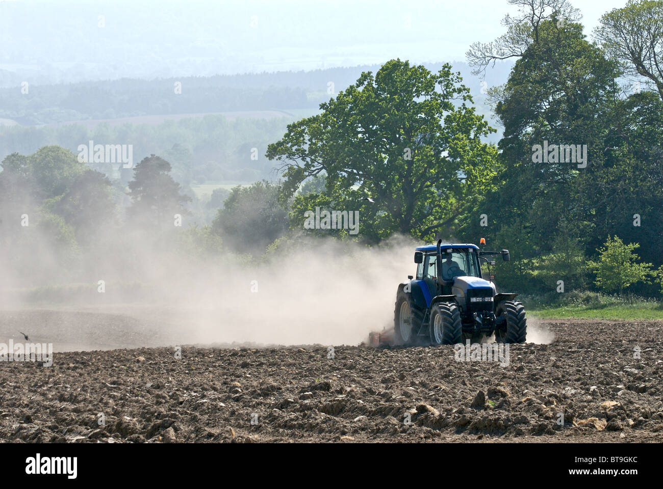 Tractor working on dry land in Sussex pulverising the soil and creating clouds of dust which is blown in the wind. Stock Photo