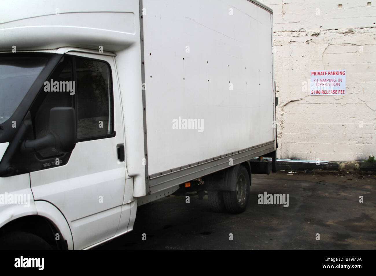 Van in private car park with clamping warning sign on wall Stock Photo