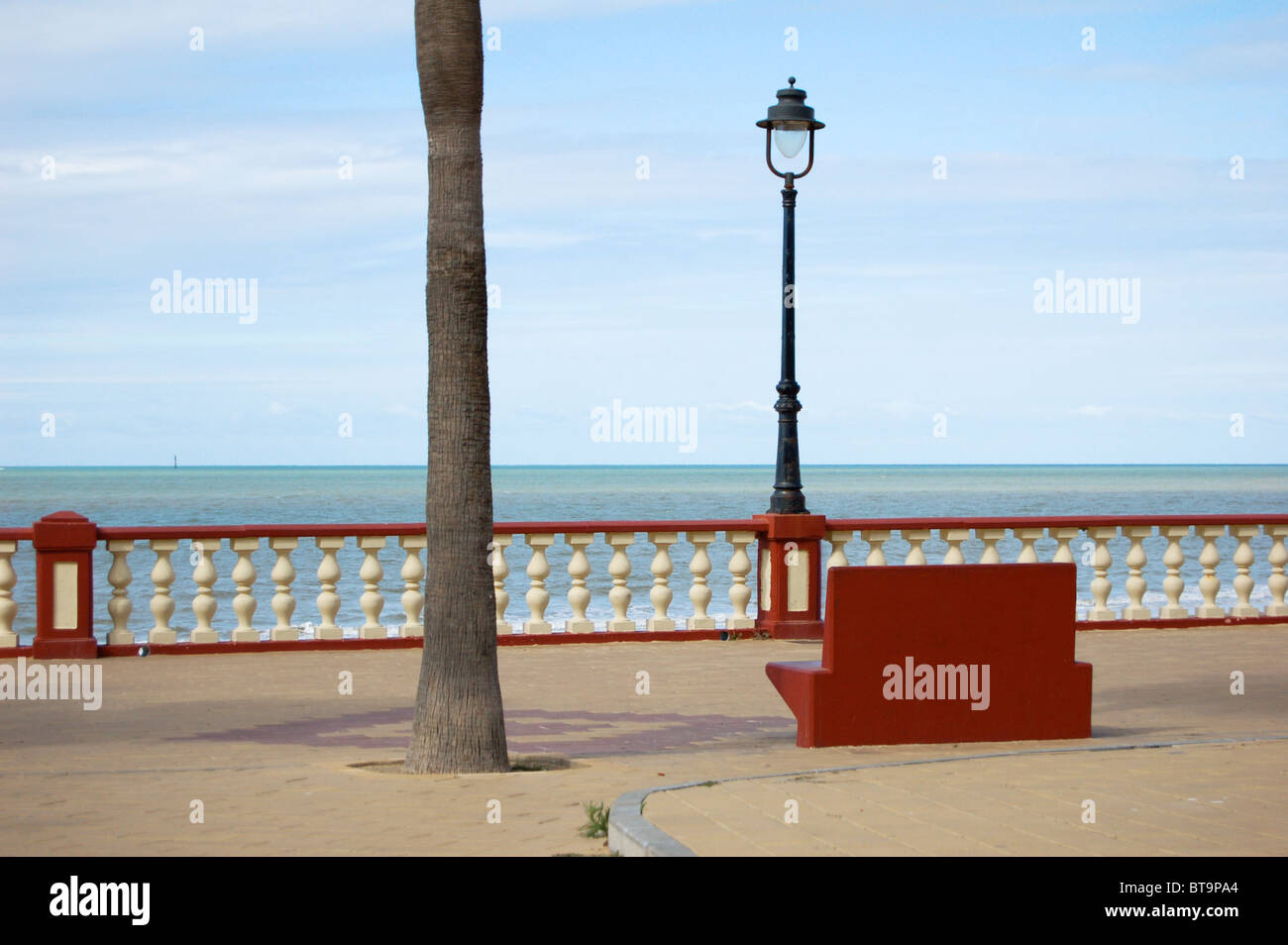 Concrete red bench looking out over Atlantic Ocean, in Chipiona, near Seville, Spain Stock Photo