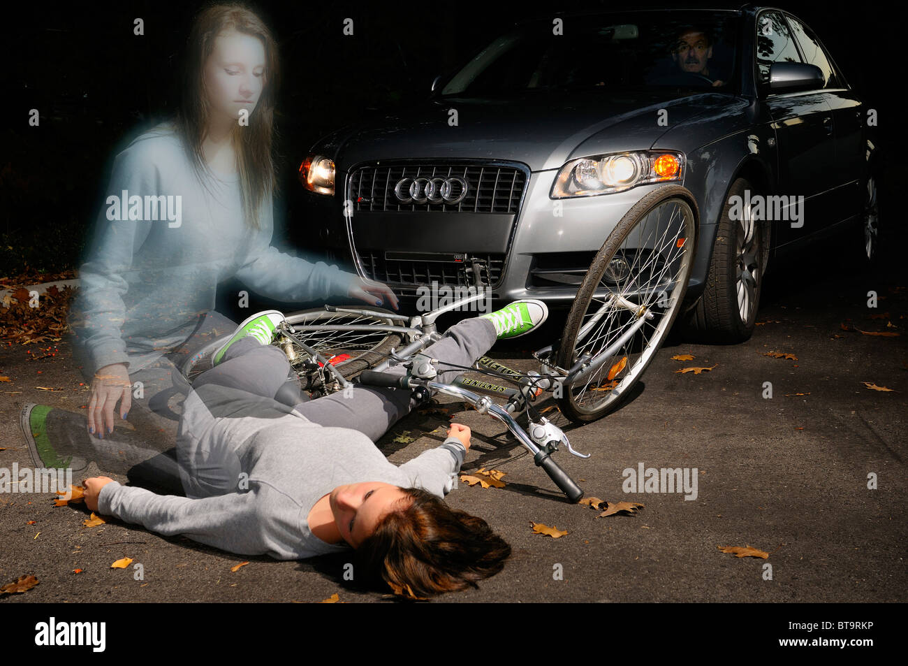 Fearful man in car stopped at a fallen young female bicyclist dead on the road with her ghost spirit rising from the accident Stock Photo