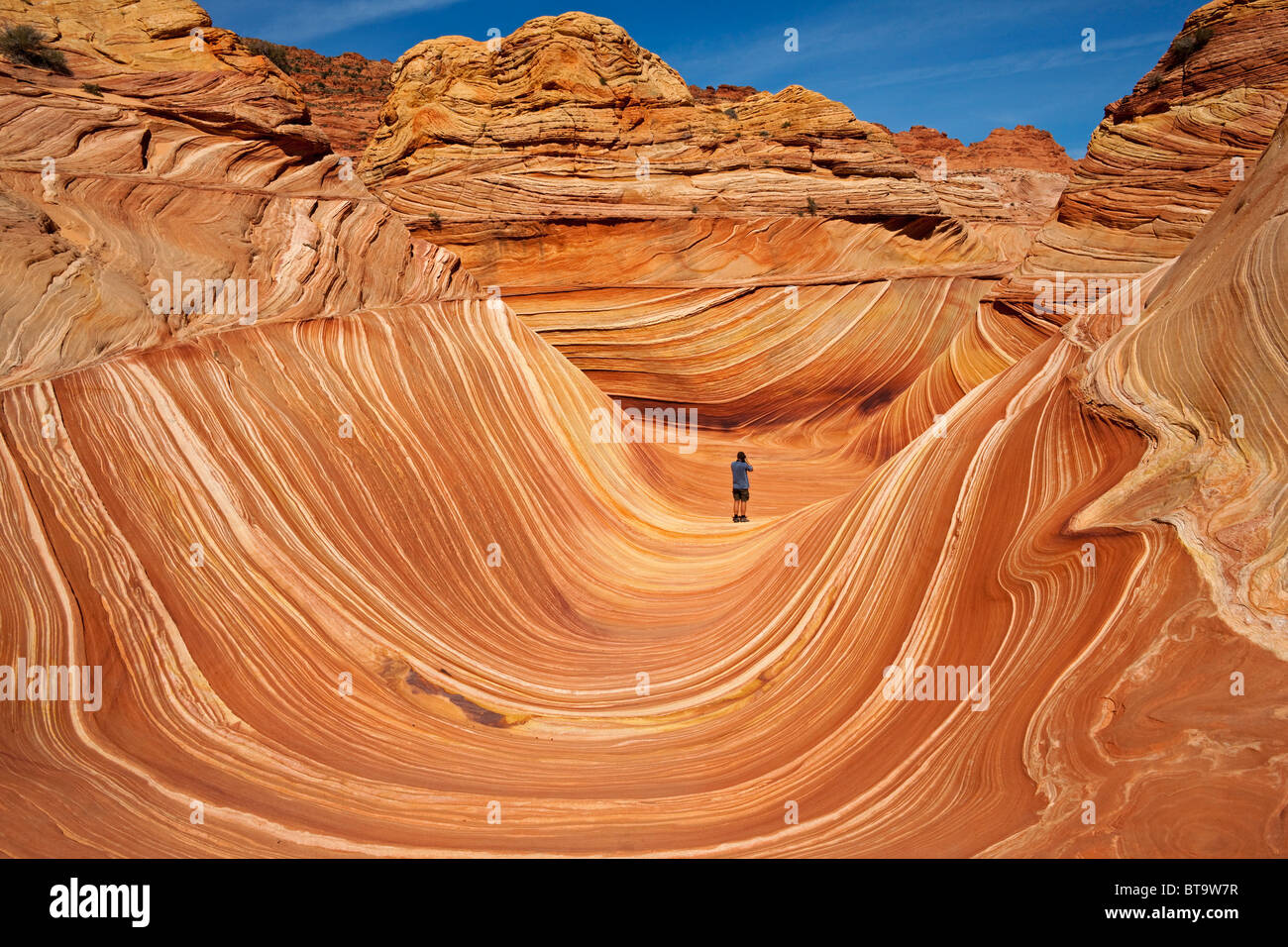 Tourist in The Wave, rock formation in Coyote Buttes North, Paria Canyon-Vermilion Cliffs Wilderness, Utah, Arizona, USA Stock Photo