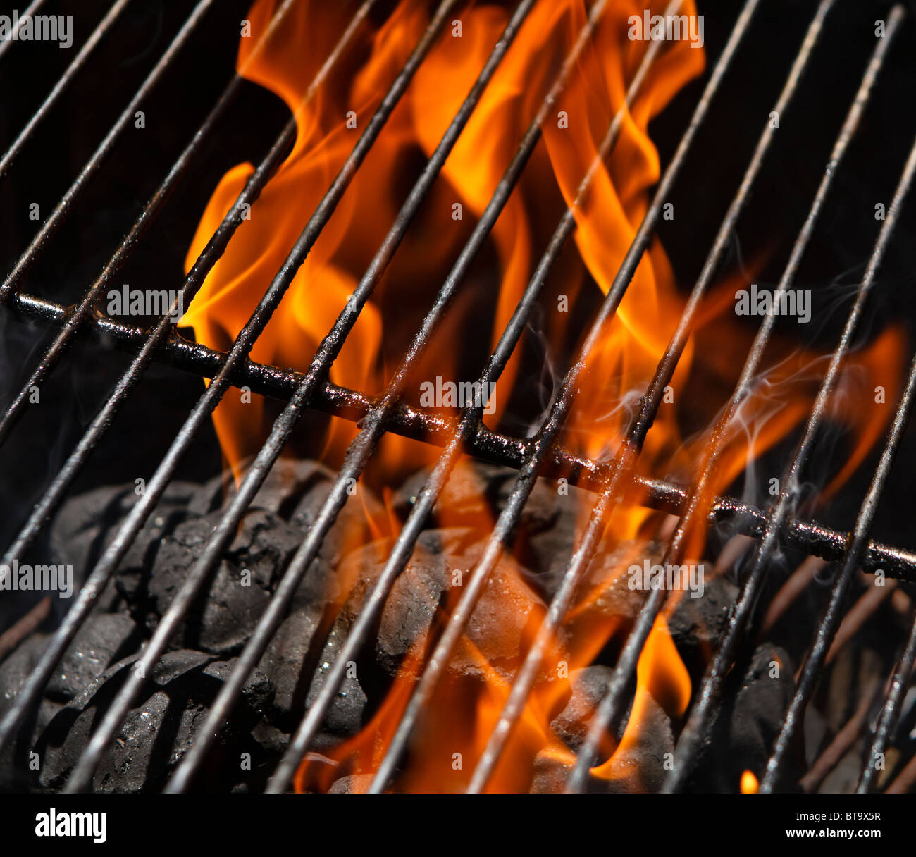 Flames in a BBQ charcoal grill after igniting the charcoal briquettes. Focus is on the grill
