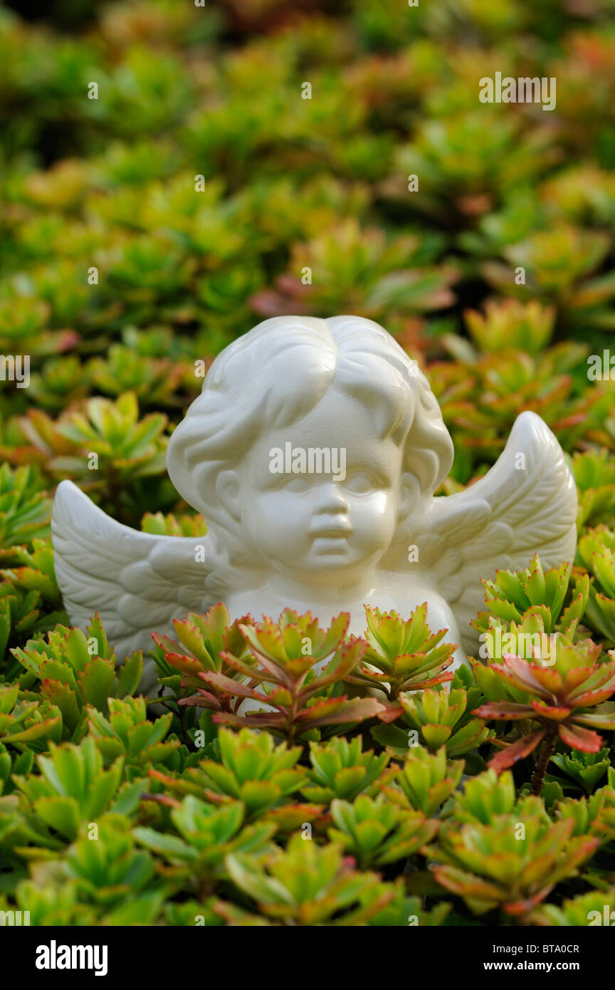 Angel figure as a garden decoration between rockery plants Stock Photo