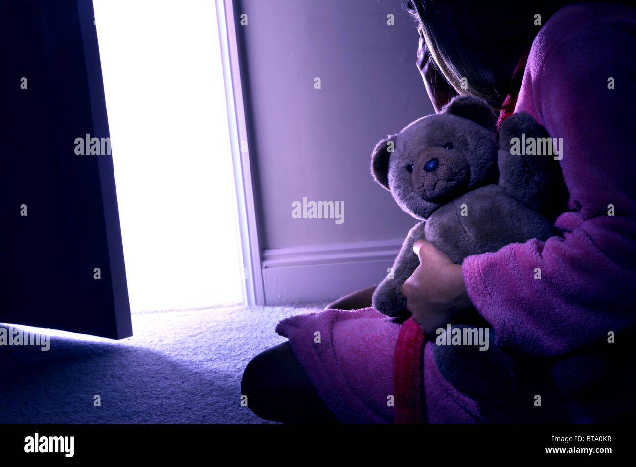 Young girl sitting holding a teddy bear, back view. Mod rel Stock Photo