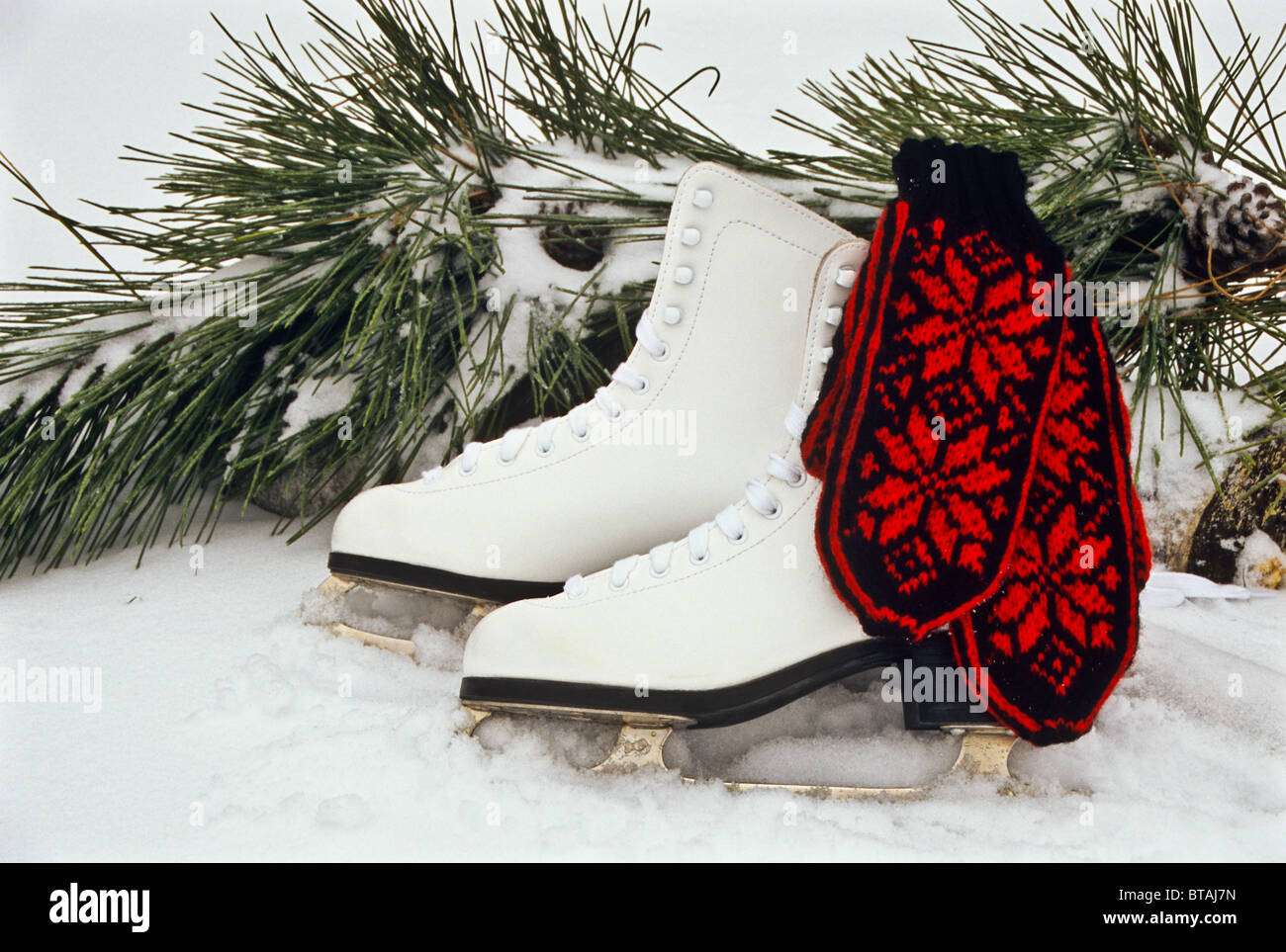 white ice skates close up and vintage knitted red woolen mittens in