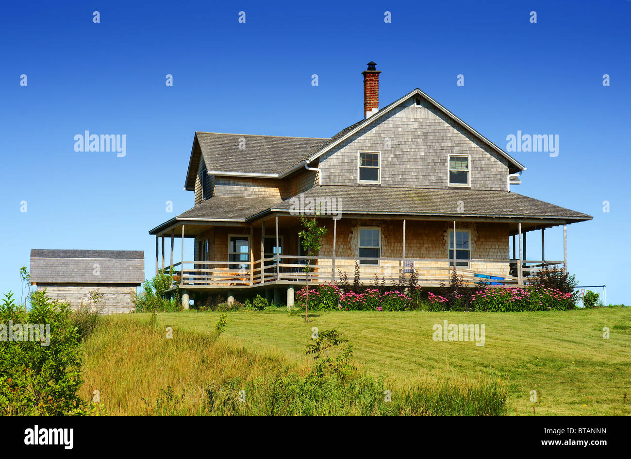Old looking cedar wood shingle farm house on top of a hill. Stock Photo