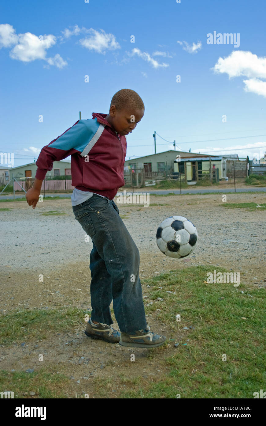 A boy plays football in Zola township in Somerset West near Cape Town, South Africa. Stock Photo