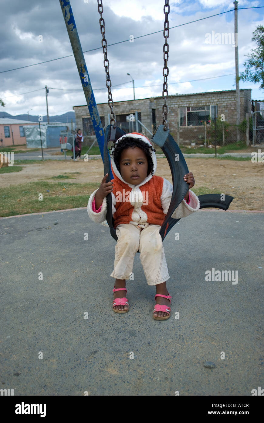 A girl plays on a swing in a Zola township, Somerset West near Cape Town, South Africa. Stock Photo