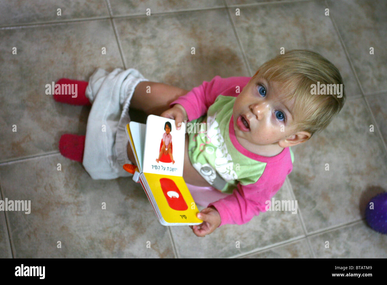 Potty training a toddler. Toddler sits on pot while reading a potty