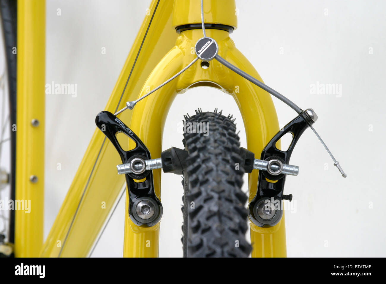 cutout closeup of front brake alloy yellow hybrid roadster trekking fitness training style bike with 700c size wheels Stock Photo