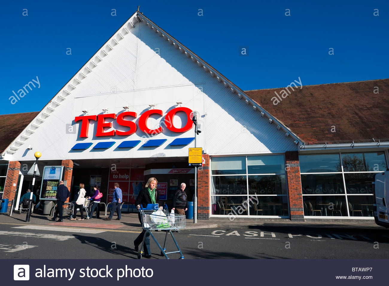 Tesco supermarket store, UK. Women pushing shopping trolley at Stock