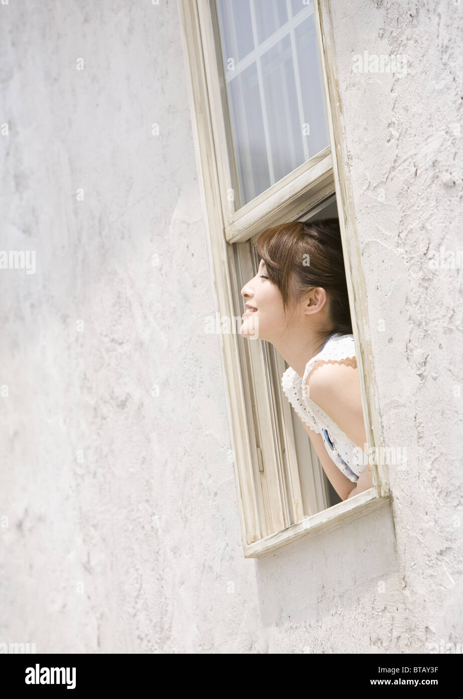 Young woman leaning out of window Stock Photo - Alamy