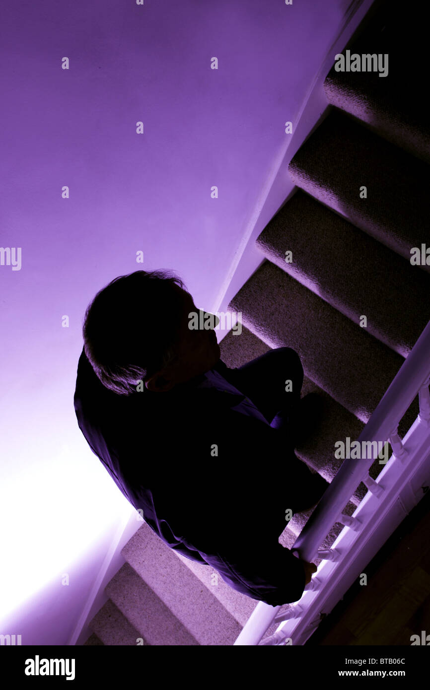 Silhouette of a man walking up a dark stairway Stock Photo