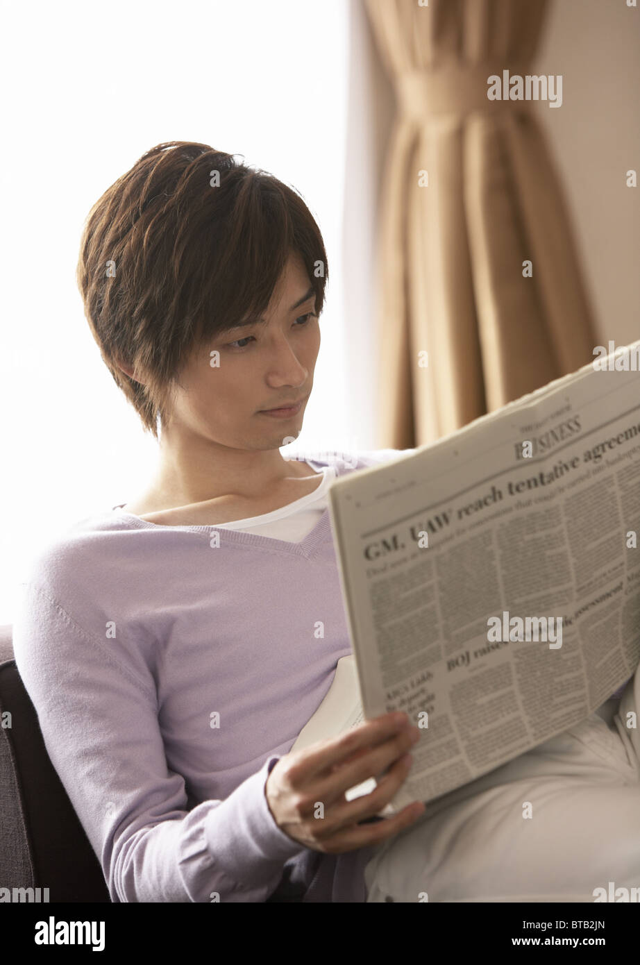 Young man reading a newspaper Stock Photo - Alamy