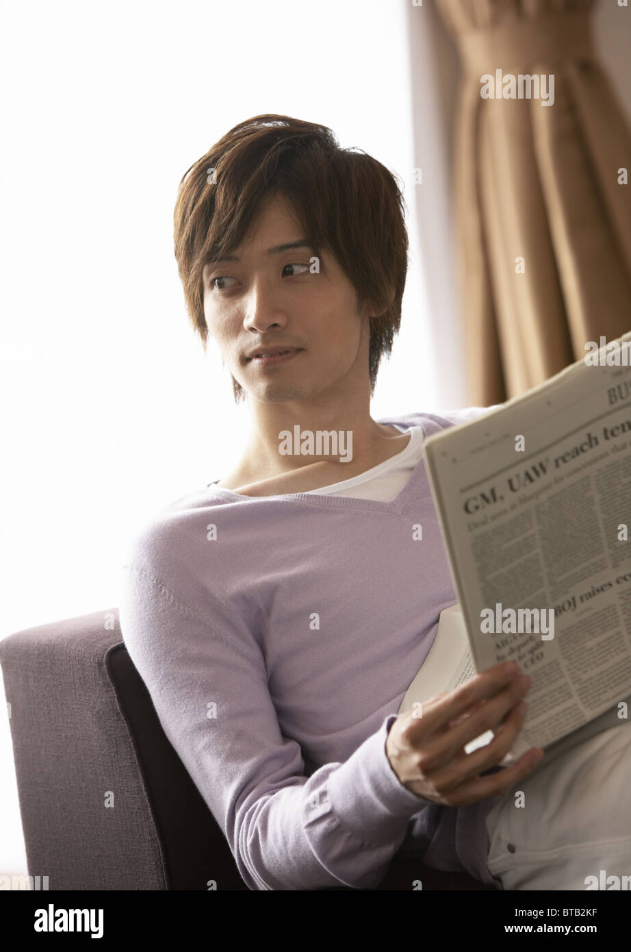 Young man reading a newspaper Stock Photo - Alamy